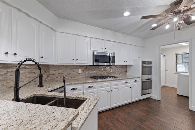 kitchen featuring white cabinets, stainless steel appliances, light stone countertops, and decorative backsplash