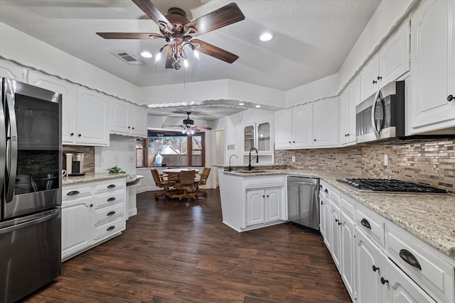 kitchen featuring light stone countertops, a textured ceiling, white cabinets, appliances with stainless steel finishes, and backsplash