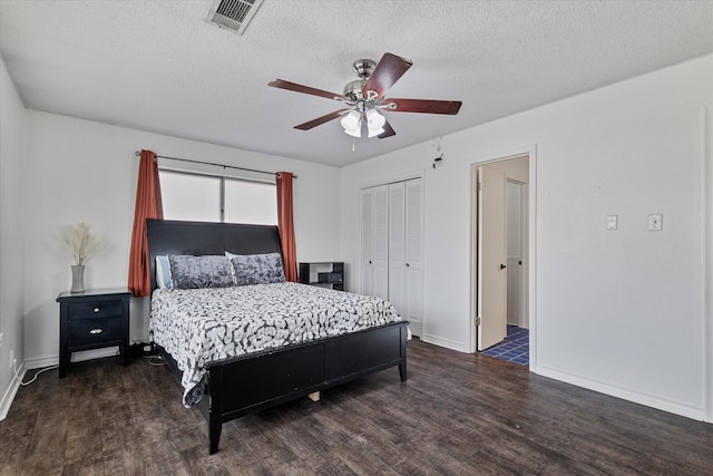 bedroom with dark wood-type flooring, a textured ceiling, a closet, and ceiling fan