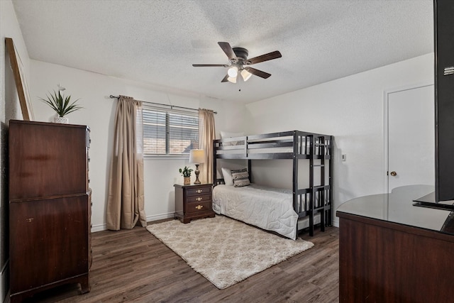 bedroom with ceiling fan, a textured ceiling, and dark hardwood / wood-style flooring