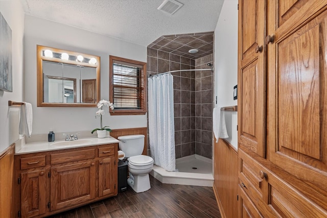 bathroom featuring toilet, a textured ceiling, wood-type flooring, curtained shower, and vanity