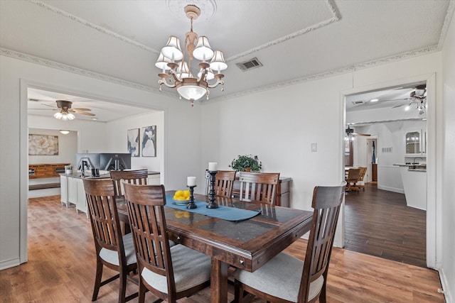 dining space with wood-type flooring, an inviting chandelier, and ornamental molding