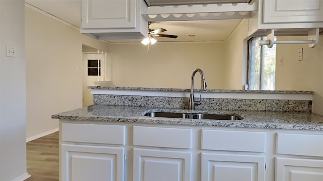 kitchen featuring ceiling fan, sink, light stone counters, light hardwood / wood-style floors, and white cabinets