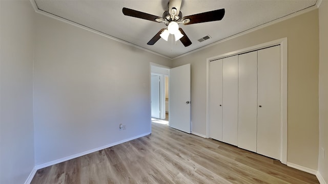 unfurnished bedroom featuring crown molding, ceiling fan, a closet, and light hardwood / wood-style floors