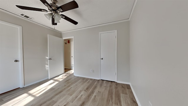 unfurnished bedroom featuring ceiling fan, light wood-type flooring, a textured ceiling, and ornamental molding