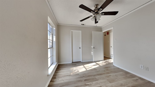 unfurnished bedroom featuring light wood-type flooring, ceiling fan, and crown molding