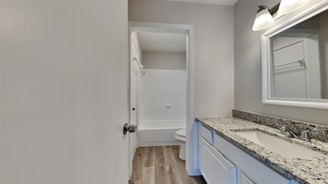 full bathroom with hardwood / wood-style floors, vanity, toilet, and tub / shower combination