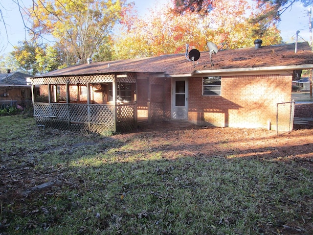 back of property with a sunroom and a lawn