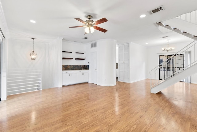 unfurnished living room featuring ceiling fan with notable chandelier, ornamental molding, and light hardwood / wood-style floors