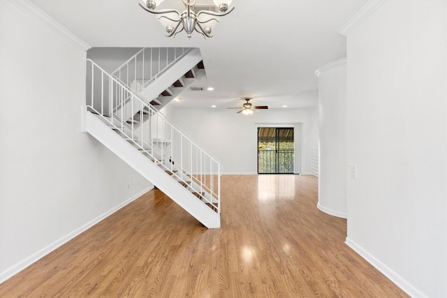 stairs with hardwood / wood-style floors, ceiling fan with notable chandelier, and ornamental molding