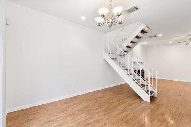 staircase with crown molding, wood-type flooring, and ceiling fan with notable chandelier