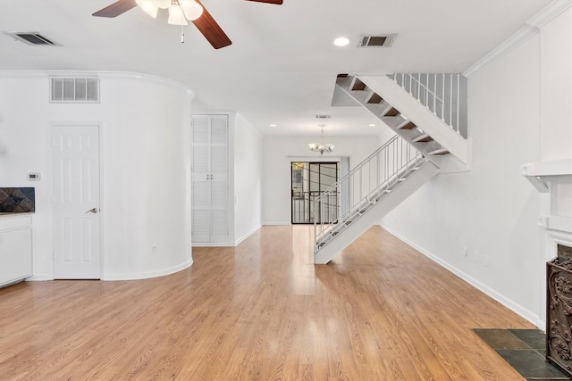 living room featuring crown molding, light hardwood / wood-style floors, and ceiling fan with notable chandelier