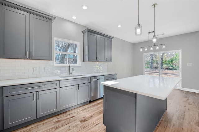 kitchen featuring gray cabinets, a kitchen island, tasteful backsplash, sink, and stainless steel dishwasher