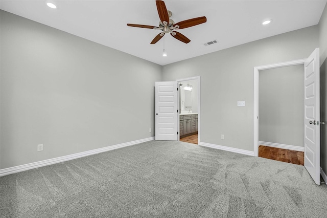 unfurnished bedroom featuring ceiling fan, light colored carpet, and ensuite bathroom