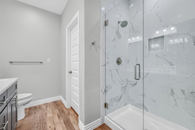 bathroom with hardwood / wood-style flooring, a shower with door, and toilet