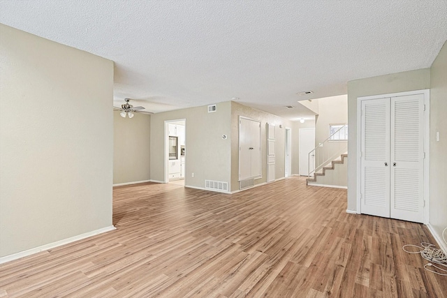 unfurnished living room with ceiling fan, a textured ceiling, and light hardwood / wood-style flooring