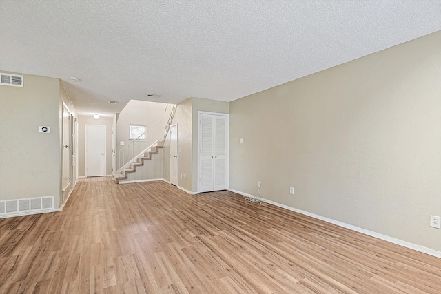 unfurnished room featuring a textured ceiling and light hardwood / wood-style flooring