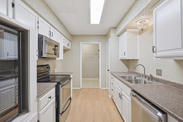 kitchen featuring light wood-type flooring, stainless steel appliances, white cabinetry, and sink