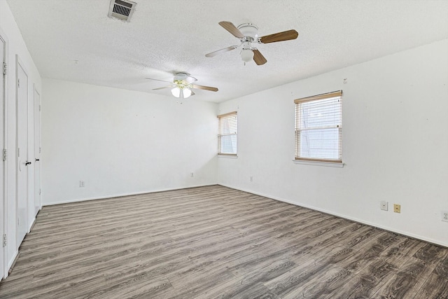 empty room featuring ceiling fan, dark hardwood / wood-style flooring, and a textured ceiling