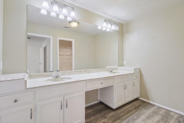 bathroom with a textured ceiling, vanity, and hardwood / wood-style flooring