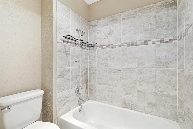 bathroom with tiled shower / bath combo and toilet