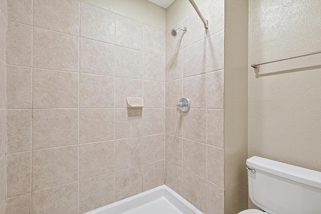 bathroom featuring tiled shower and toilet