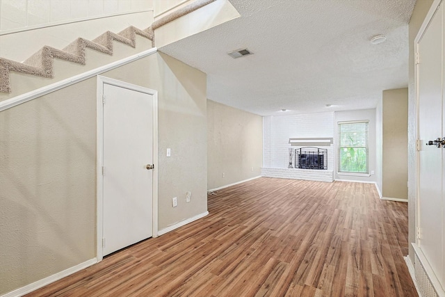 unfurnished living room with a fireplace, wood-type flooring, and a textured ceiling