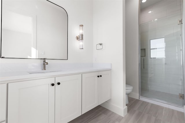 full bathroom with toilet, a shower stall, baseboards, and vanity