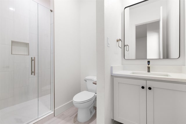 bathroom with baseboards, a shower stall, toilet, and vanity