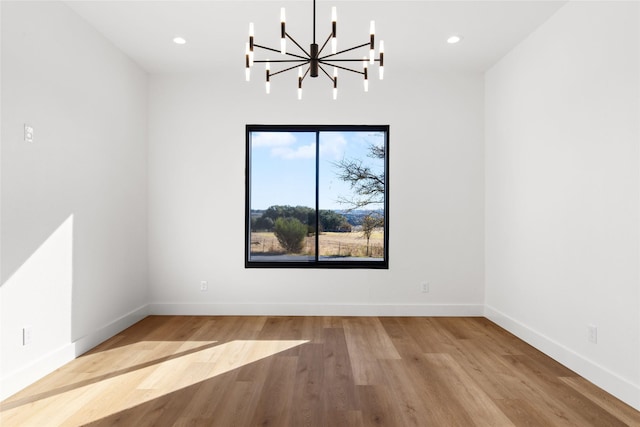 empty room featuring an inviting chandelier, baseboards, wood finished floors, and recessed lighting