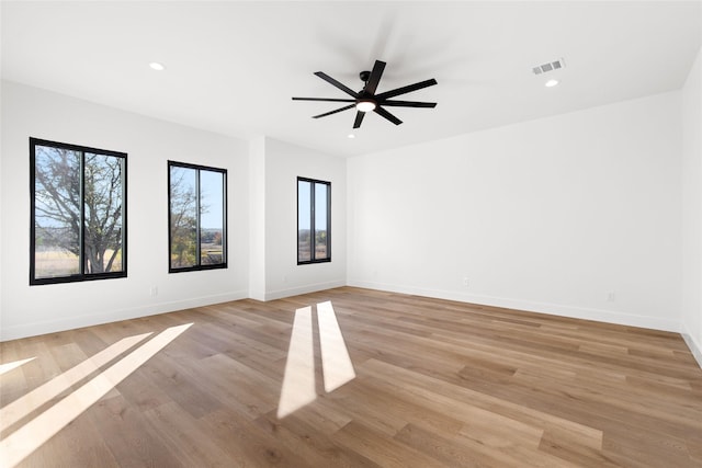 empty room featuring light wood-style floors, recessed lighting, visible vents, and baseboards