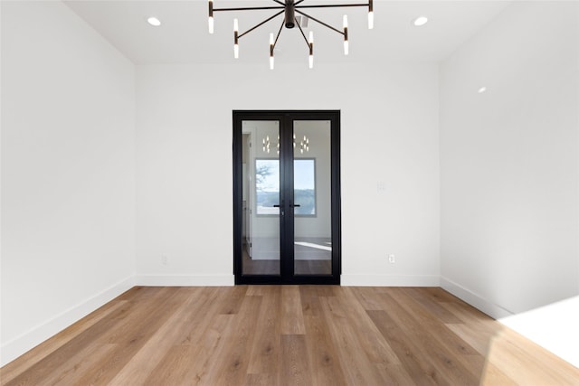 empty room with light wood finished floors, baseboards, and french doors