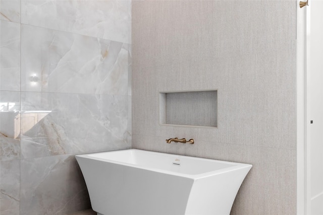 bathroom with a freestanding tub and tile walls