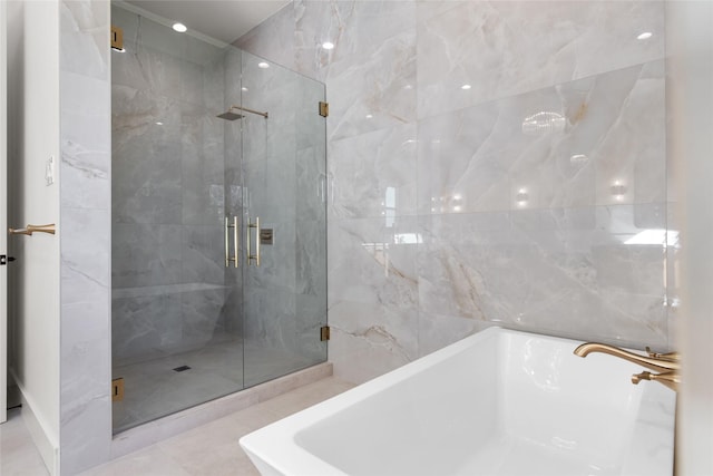 full bathroom with a shower stall, a bathtub, and tile walls