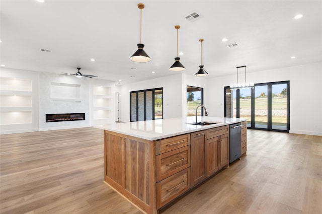 kitchen featuring built in features, a fireplace, recessed lighting, light wood-style floors, and a sink