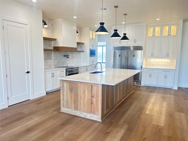 kitchen featuring light wood-style floors, high end appliances, a sink, and light countertops