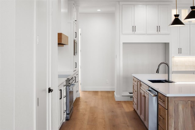 kitchen featuring light wood finished floors, light countertops, backsplash, white cabinets, and a sink