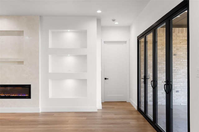 hallway with baseboards, a healthy amount of sunlight, wood finished floors, and built in features