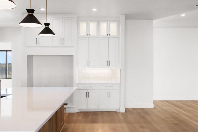 kitchen with light wood finished floors, decorative backsplash, light countertops, white cabinetry, and recessed lighting