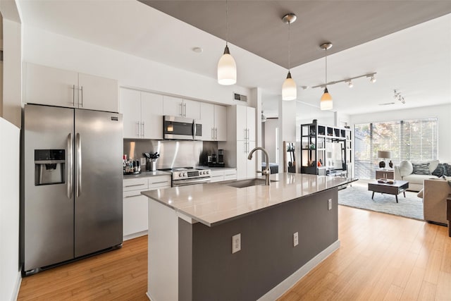 kitchen featuring stainless steel appliances, sink, decorative light fixtures, light hardwood / wood-style flooring, and white cabinets