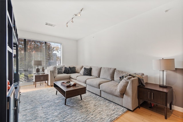 living room with rail lighting and light hardwood / wood-style floors