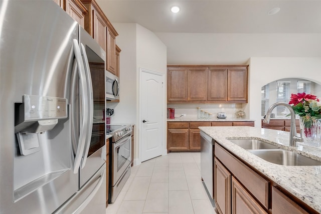 kitchen featuring light stone counters, stainless steel appliances, sink, and light tile patterned floors