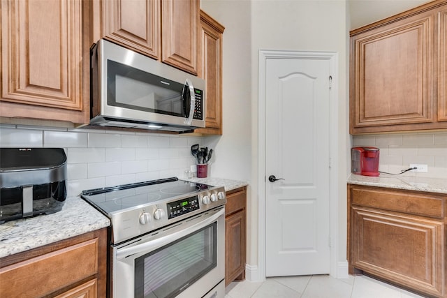 kitchen featuring tasteful backsplash, appliances with stainless steel finishes, and light stone countertops