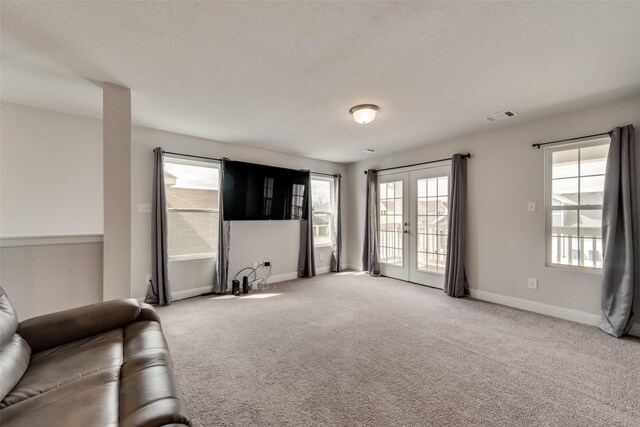 unfurnished living room with light carpet, french doors, and a wealth of natural light