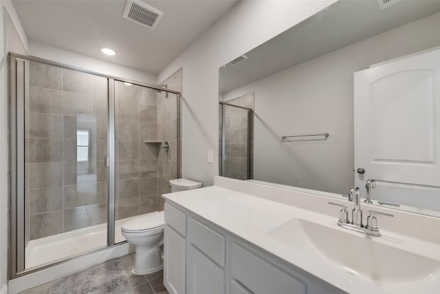 bathroom featuring tile patterned flooring, vanity, an enclosed shower, and toilet