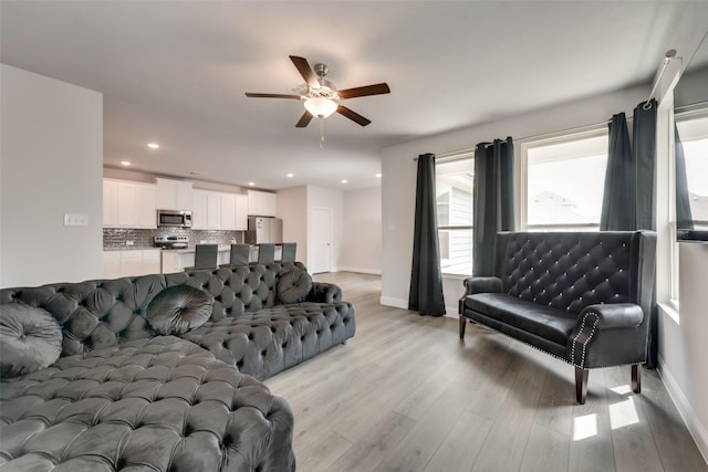 living room with ceiling fan and light wood-type flooring