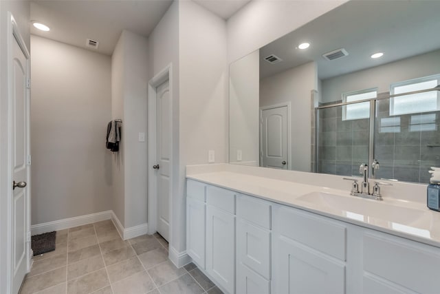 bathroom with a shower with door, vanity, and tile patterned flooring