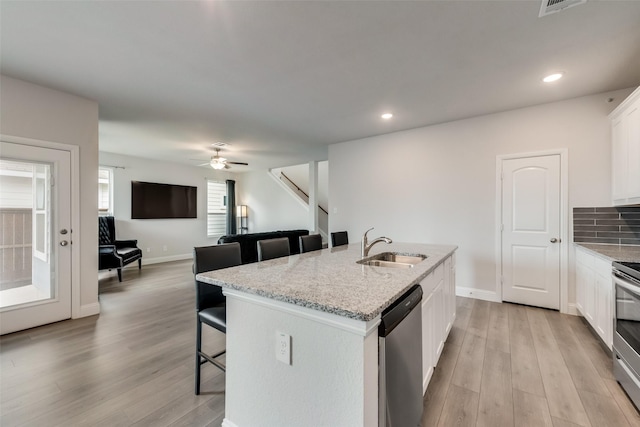 kitchen featuring white cabinets, sink, an island with sink, appliances with stainless steel finishes, and a breakfast bar area