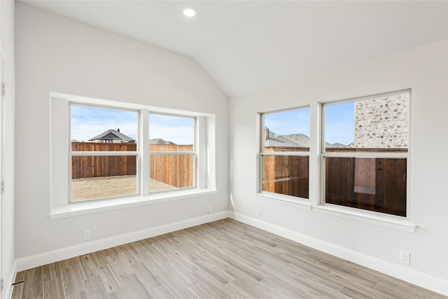 unfurnished room with vaulted ceiling, light hardwood / wood-style flooring, and a wealth of natural light