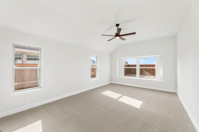 carpeted spare room featuring ceiling fan, lofted ceiling, and a wealth of natural light